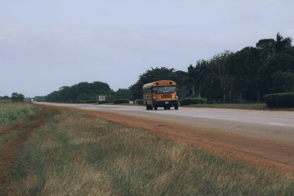A yellow school bus driving along a country road